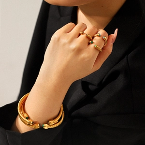 Detailed view of gold twisted cable bracelet and rings set with natural malachite and agate