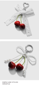 Detail of red cherry keychains with lace and pearl bows on a silver metal ring