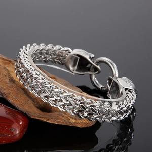 Detailed close-up of a silver punk skull buckle and metal woven chain on a wooden base