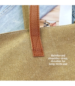 Detail of khaki canvas bag showing reinforced leather strap and cross-stitching