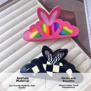 Detail of heart-shaped acetate hair claws in pink rainbow and black checkered patterns