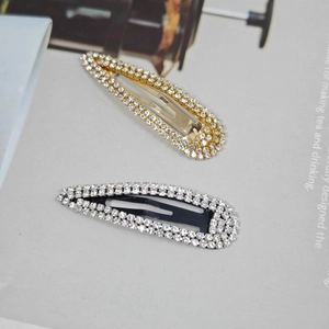 Detail of drop-shaped rhinestone hair clips set in gold and black metal plating