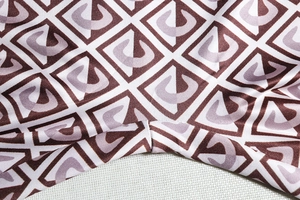 Macro shot of high-elasticity dark brown fabric with geometric letter print and seam stitching