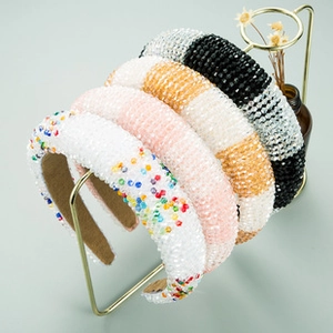 Detail showing four sparkling rhinestone headbands in white, pink, gold and black colors