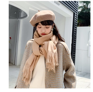 Close-up of beige cashmere feel scarf with tassels paired with a stylish wool beret
