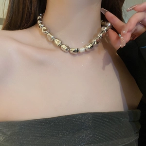 Detailed view of silver irregular metal beads necklace with a white pearl on the neck