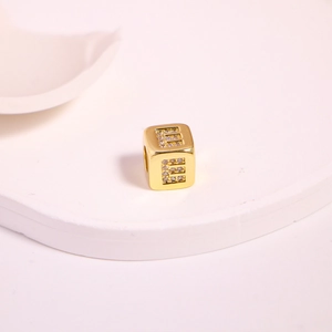 Detail of square gold bead with letter E inlaid with sparkling cubic zirconia crystals