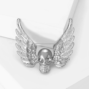 Gothic silver wing brooch with skull and white rhinestones on minimalist white display