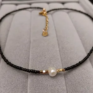 Minimalist freshwater pearl necklace with black beads and gold-tone spacers on display