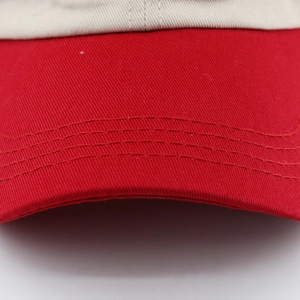 Gros plan sur les coutures de la visière en coton rouge d'une casquette bicolore