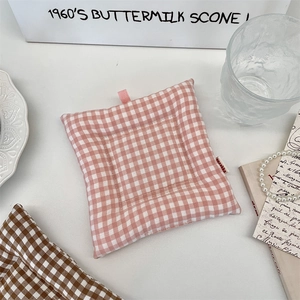 Gros plan sur un dessous-de-plat en tissu matelassé à carreaux roses avec boucle