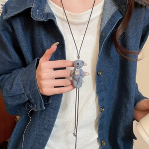 Détail de la cravate bolo ours en denim avec un grand strass sur une veste bleue