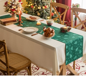 Detail of green Christmas tree pattern table runner with elegant cream lace trim borders