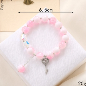 Pink glass beaded bracelet featuring heart lock and key charms on a white display stand