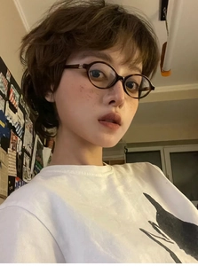 Close-up of tortoise shell oval frame glasses worn by a person in a retro Y2K style