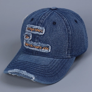 Detailed macro view of distressed denim baseball cap with orange embroidery and frayed holes