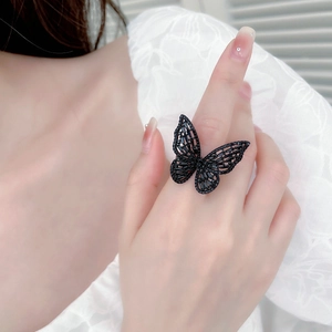 Macro view of a 3D hollow black butterfly ring with sparkling crystals on a hand