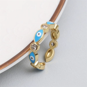 Detail shot of adjustable gold rings with blue evil eye motifs and sparkling white zircons