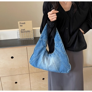 Détail du sac hobo en jean bleu avec coutures radiales et fermeture éclair en métal