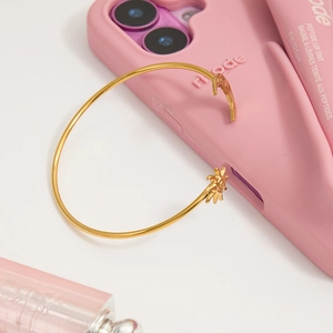 Détail du bracelet doré soleil et lune sur coque rose avec finition métallique élégante