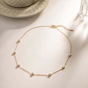 Detail of gold titanium steel necklace with round zircon accents and a lobster clasp