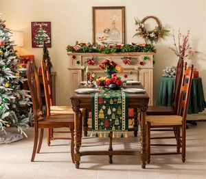 Green Christmas table runner with festive tree patterns and gold tassels in a cozy dining setting