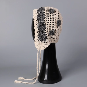 Detail of handmade beige crochet bonnet with black flowers and hollow knit texture