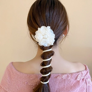 Detailed view of a sweet white flower scrunchie and telephone wire hair tie on brown hair.