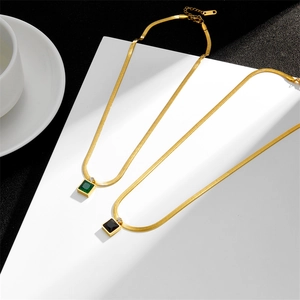 Detail of gold flat snake chains with green and black square gemstone pendants