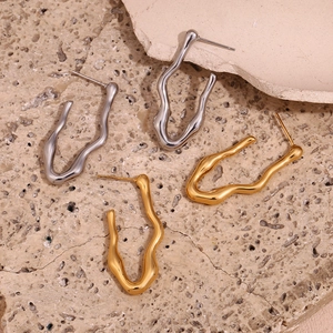 Close-up of irregular wave-shaped hoop earrings in polished gold and silver finishes