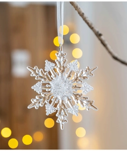 Close-up of transparent acrylic snowflake ornament hanging with a white ribbon