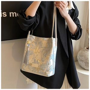 Detail of floral jacquard fabric on shoulder bag with leather label and grey tassel charm