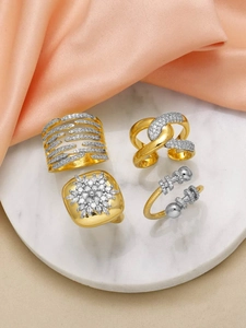 Detailed view of four 18k gold plated copper rings with white cubic zirconia on marble base