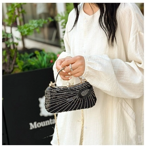 Detail of a vintage black evening clutch with sequin sunburst design and gold chain strap