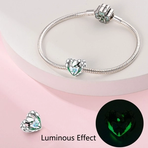 Détail d'un charme cœur argenté lumineux avec motif papillon sur un bracelet chaîne serpent