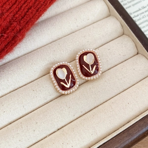 Detail of red enamel firework earrings with white tulip center and pearl border decoration