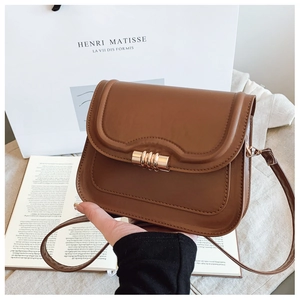 Détail du sac selle marron caramel avec rabat vague et fermoir cylindrique doré