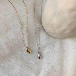Dettaglio di pendenti a goccia in oro e argento lucido su tessuto bianco