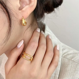 Close-up of golden geometric chain ring and chunky drop earring on model