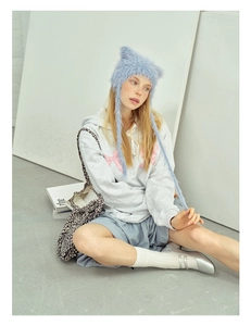Detail of light blue plush cat ear knit hat with long braided tassels on a model
