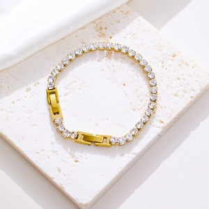 Detailed close-up of golden evil eye bracelet with white zircons on white stone
