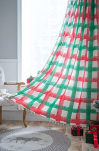 Close-up of red and green plaid curtain featuring decorative white tassel fringe details