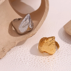 Macro shot of silver and gold heart rings with artistic water droplets on metal surface