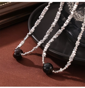 Macro detail of irregular silver block chain with a round tiger eye stone pendant