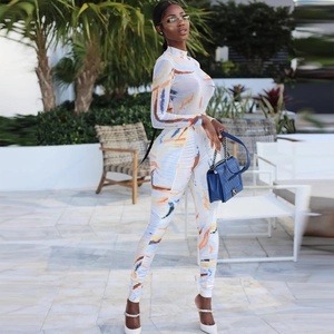 Detail of long sleeve jumpsuit with abstract orange and blue print on white fabric
