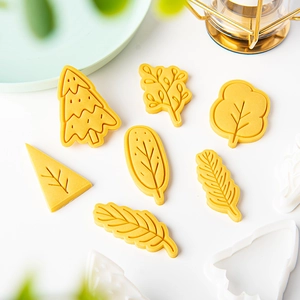 Cartoon Christmas tree and leaf cookie cutter set with yellow dough shapes for DIY baking
