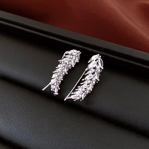 Macro detail of silver feather earrings with sparkling zircons and white faux pearls