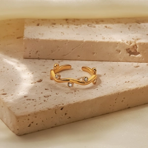Detailed view of an 18K gold open ring with leaf-like waves and sparkling cubic zirconia
