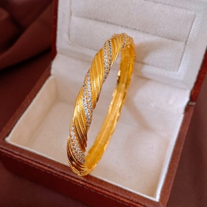 Detail of gold-plated twisted bangle featuring rows of sparkling cubic zirconia in a jewelry box