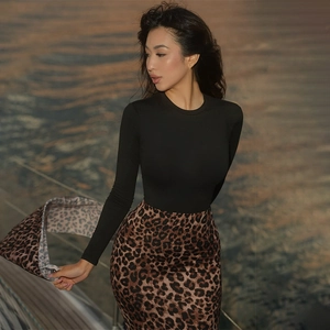 Detail of slim-fit leopard print skirt and black long-sleeve top in sunset light